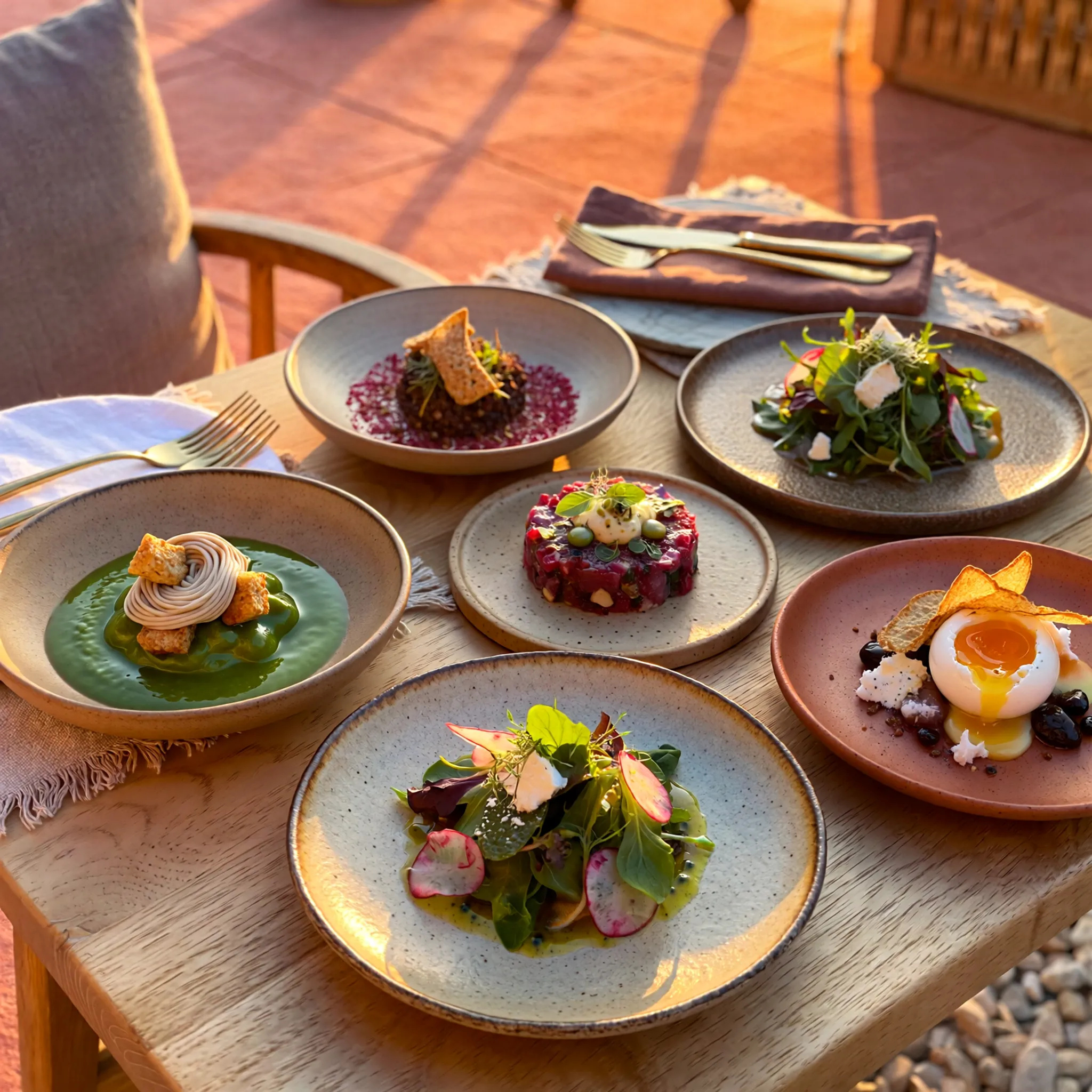 Galerie de plats gastronomiques colorés servis en terrasse au coucher du soleil