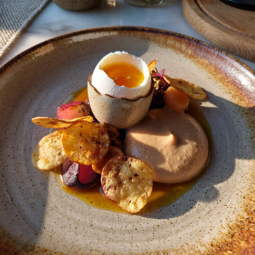 Oeuf parfait bio cuit à 64 °C avec chips de légumes et crème, dressage gastronomique mettant en valeur les produits et la présentation du plat.